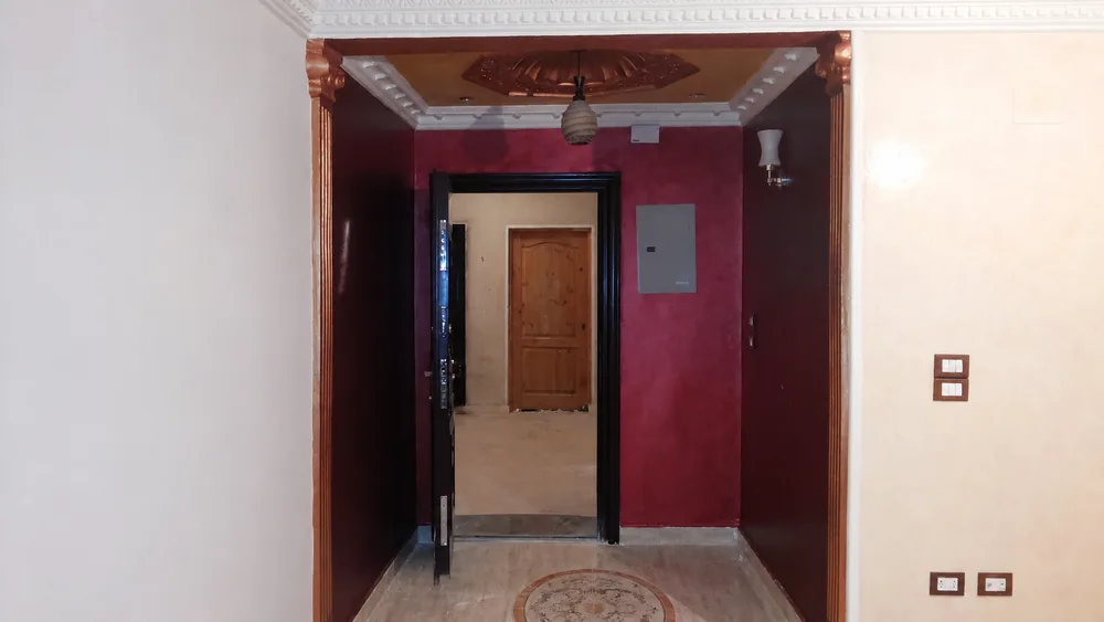 ممر بحوائط عنابية وأبواب خشبية وتفاصيل جبس كلاسيكية